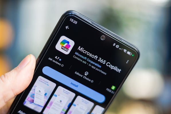 A hand holding a smartphone displaying the Microsoft 365 Copilot