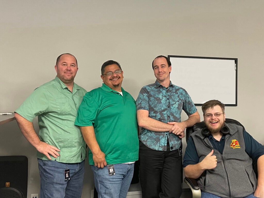 4 men working in technology jobs pose for a picture.
