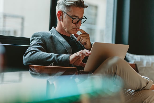 Finance professional reviewing a vendor payment email on a laptop, illustrating business email compromise risk